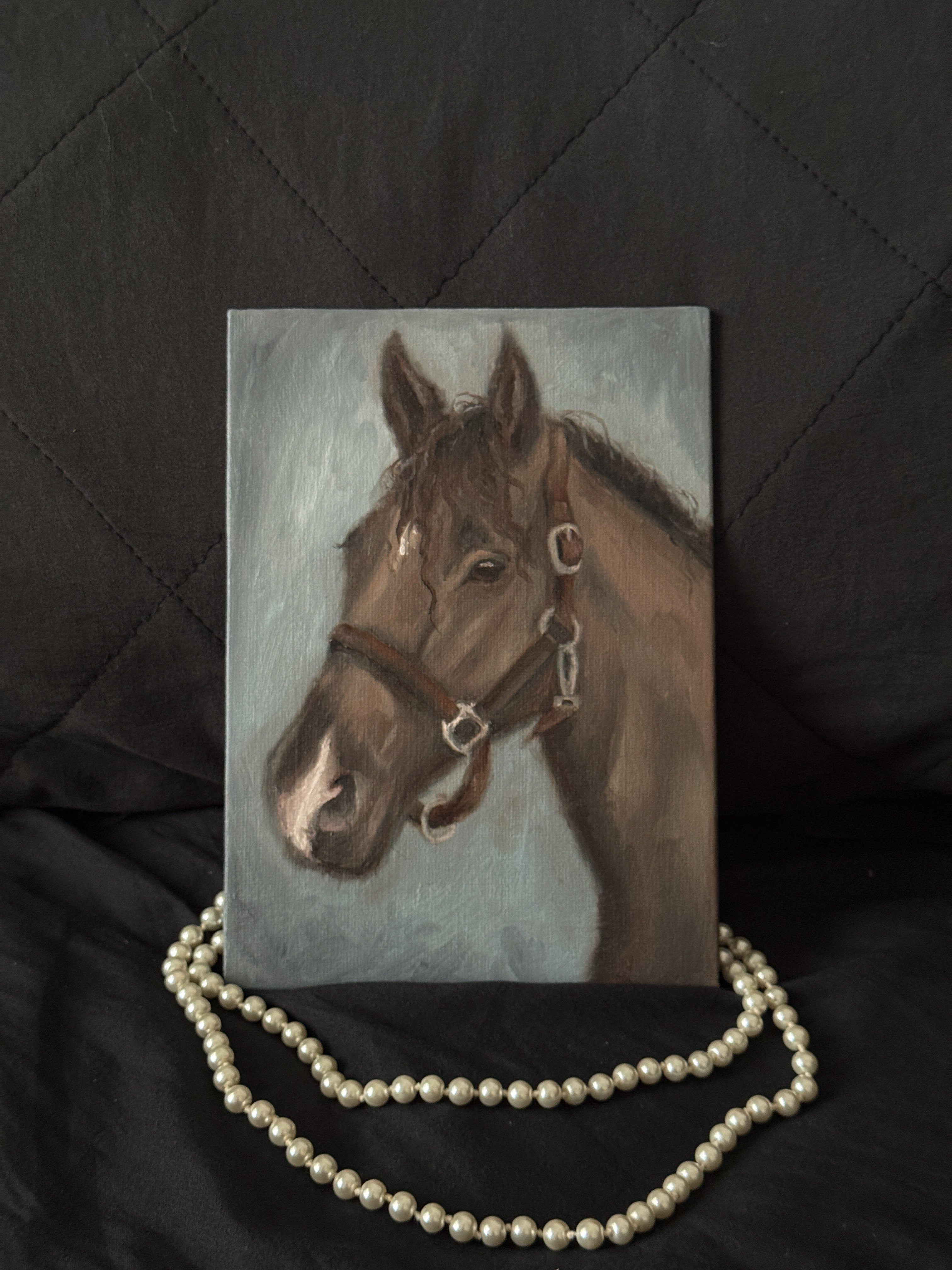 Painting of a horse with a bridle on a dark surface with pearls.