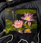 Oil painting of pink water lilies on a dark surface with pearls in the background