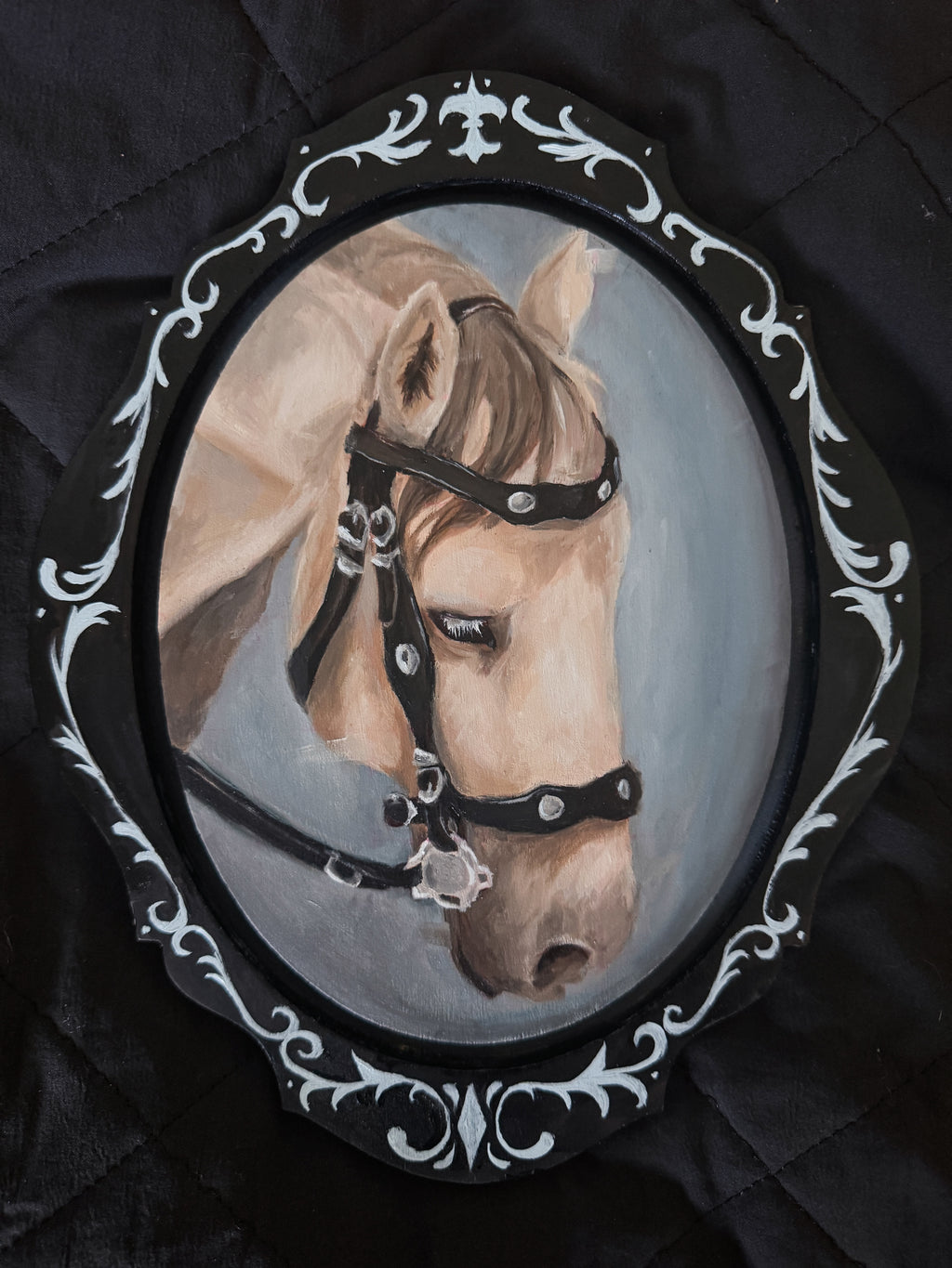 Painting of a horse's head in an ornate frame on a dark background